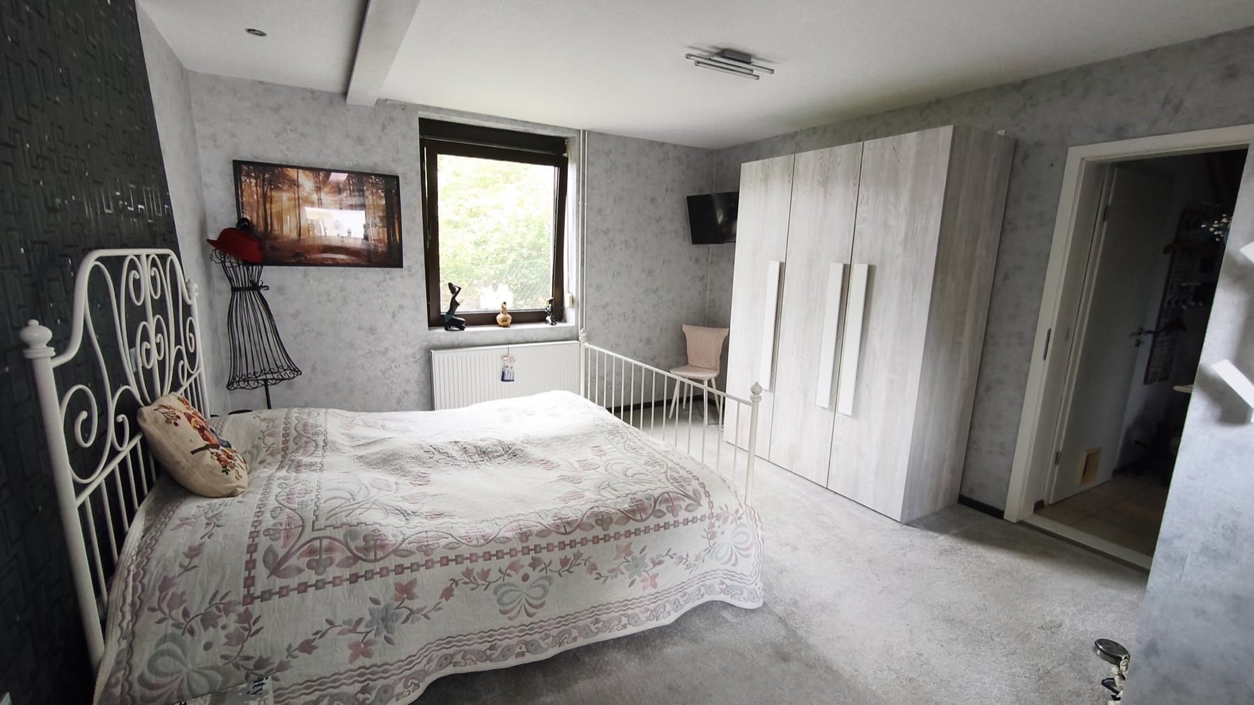 Schlafzimmer mit Kleiderschrank und Fenster ins Grüne