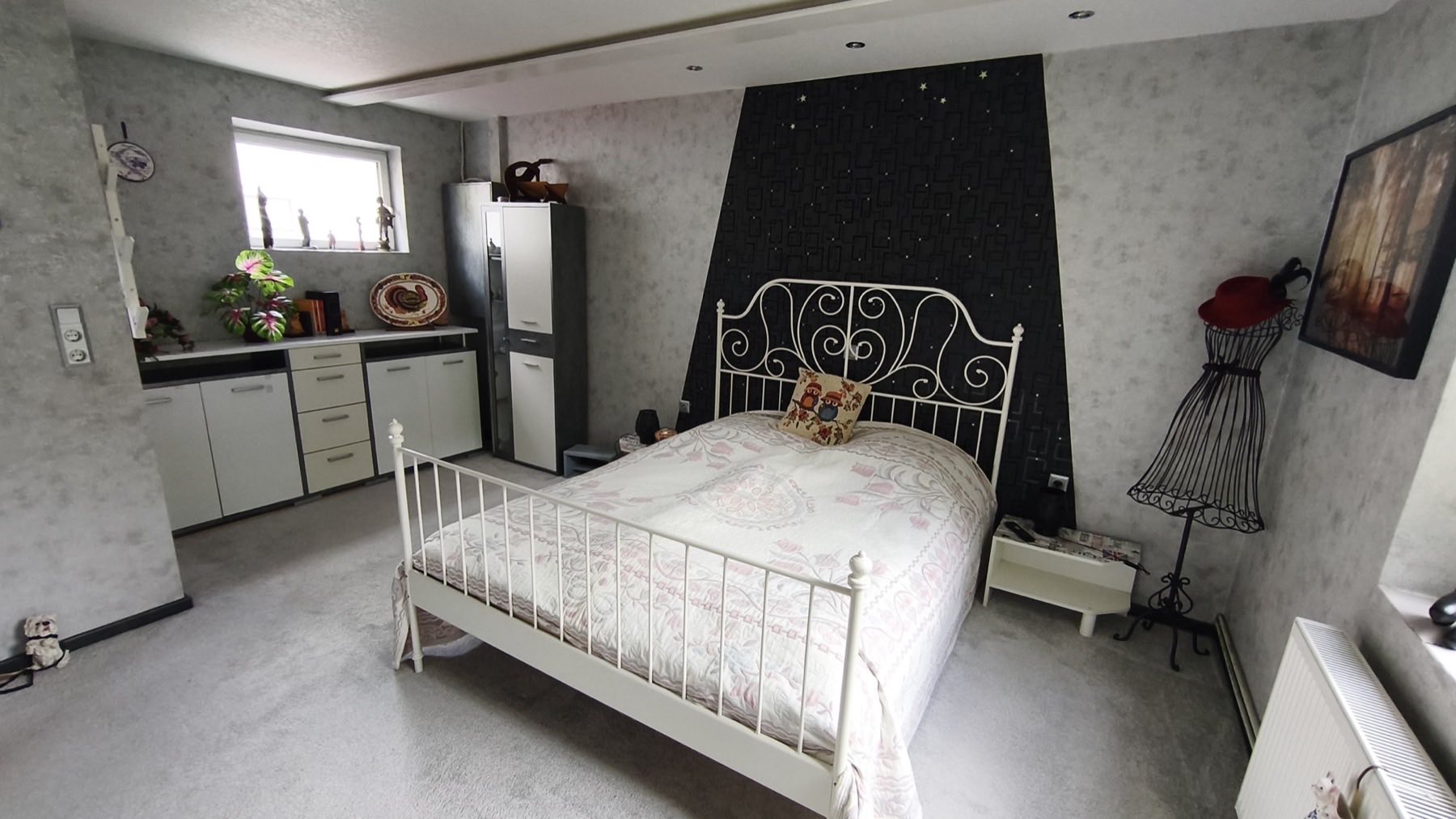 Schlafzimmer mit weißem Metallbett vor der Sternenhimmel-Wand